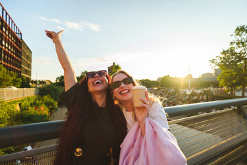 Two friends laughing, having fun outdoors with takeaway coffee at golden hour © pablo