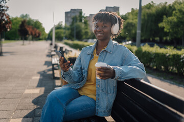 Obraz premium Young woman enjoying music and coffee in park