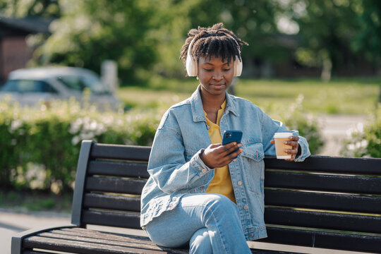 Young woman enjoying music and coffee in park