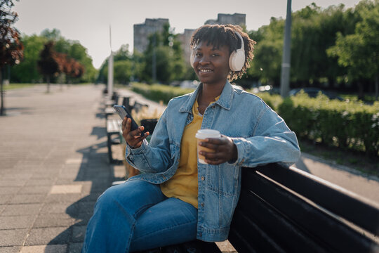 Young woman enjoying music and coffee in park