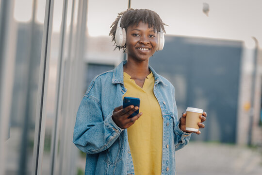 Young woman enjoying music and coffee in city
