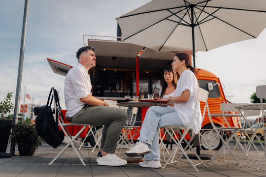 Friends talking and enjoying coffee at city food truck