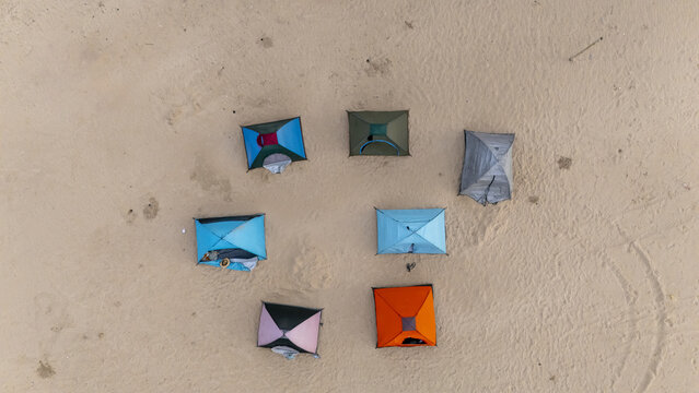 Aerial view of colorful tents arranged in a circle on the sandy shore of Tarkwa Bay Beach in Lagos, Lagos, Nigeria.