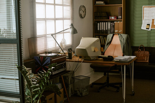 Empty retro office workspace featuring vintage computer monitor on wooden desk with swivel chair. Image represents corporate history and is suitable for business heritage marketing