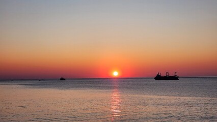 Naklejka premium East Sea Sunrise Calm: A peaceful sunrise over the calm horizon of the East Sea, where morning sunlight spreads a reddish glow across the water to bring quiet serenity.