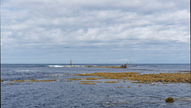 The Steel Navigation Beacon and wreck of the Sovereign Fishing Boat on the rocks at Cairnbulg Point in Fraserburgh Bay at Low Tide.