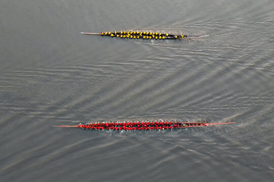 Aerial view of a traditional boat race with two long wooden boats carrying rowers in yellow and red uniforms on the river in Gopalganj, Dhaka Division, Bangladesh.
