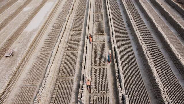 Aerial view of workers carrying bricks in a large brick field in Dhaka, Bangladesh.