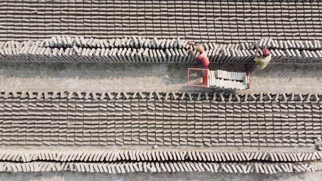 Aerial view of workers transporting bricks in a large brick field in Dhaka, Bangladesh.