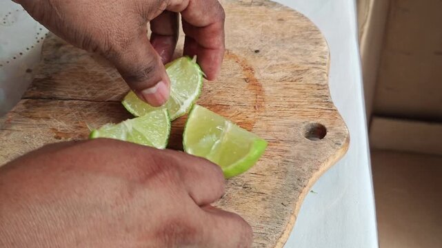 Hands Placing Four Fresh Lime Slices on Wooden Cutting Board