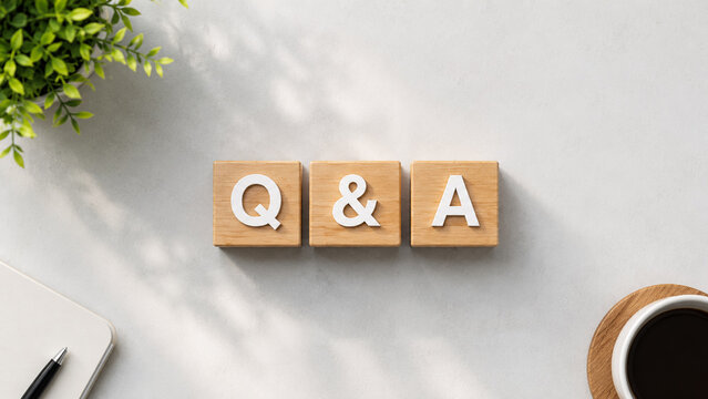Top view of q and a wooden blocks on office desk with coffee and notebook.