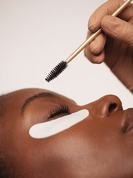 Mascara wand brushing eyelash extensions with under eye patch, finishing touch on lash treatment beauty macro closeup