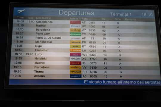 Departure flight information display board at Milan airport showing various international destinations and airlines with scheduled times