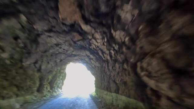 Car exits rock tunnel, forward view onto a mountain road in Svaneti, Georgia, illustrating transport engineering, remote regional access and infrastructure connecting highland destinations