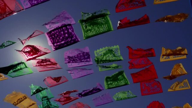 Papel picado decorations flying in the sky over Mexico during the day