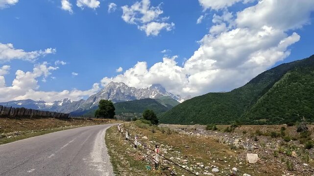 Traveler drives toward Mazeri, forward view of snowcapped Caucasus peaks in Svaneti, Georgia, promoting rural tourism, trekking access, local guesthouse stays and mountain destination planning