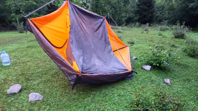 Wet tent dries outdoors, wide view of camping shelter aired over a frame on grass in Svaneti, Georgia, demonstrating gear maintenance, moisture control and equipment care after mountain trekking