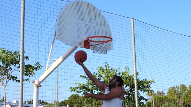 Athletic man scoring a point in outdoor basketball court