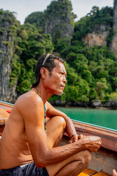 Thai man contemplating on a longtail boat in a tropical island