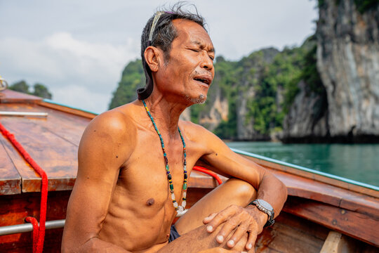 Thai senior man relaxing on traditional longtail boat