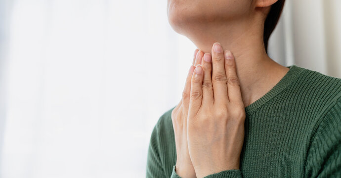 Woman touching her throat with both hands. Representing throat discomfort, health awareness, wellness and healthcare concerns.