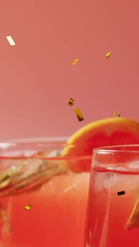 Animation of confetti falling and cocktail on pink background