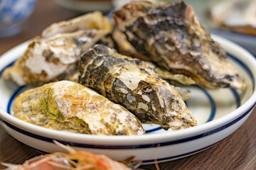 Fresh oysters in rough shells served on a ceramic plate © Bambi and Sunny