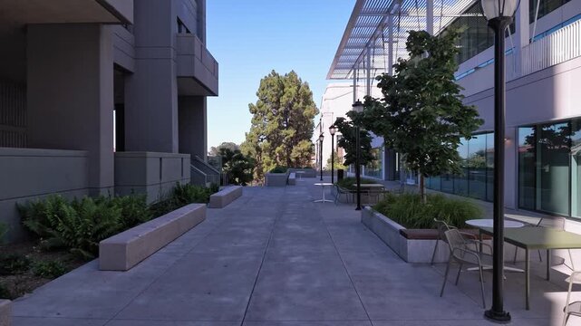 Modern architecture of the University of California, Berkeley campus, with a concrete walkway leading through an empty plaza flanked by contemporary buildings on a bright, sunny day
