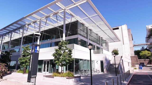Moving shot of the modern facade of Chou Hall, part of the Haas School of Business at the University of California, Berkeley, on a bright sunny day against a clear blue sky