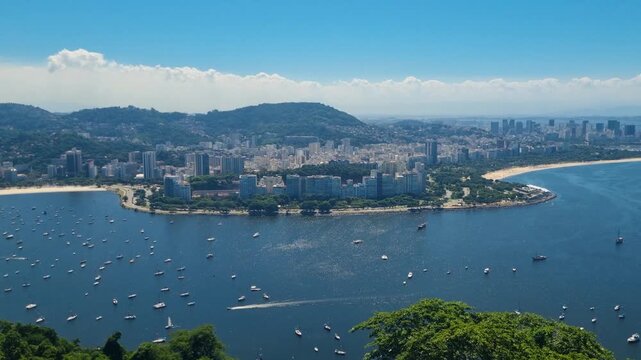 Panoramic view from Sugarloaf Mountain across Botafogo and Flamengo Beach in Rio de Janeiro, with small boats anchored on the blue Atlantic Ocean and the cityscape stretching along the coastline