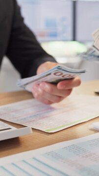 Employees counting cash salary payroll payment in office. Money changes hands over payroll documents and calculator. Suitable for wages topics and finance content. Clear finance concept.