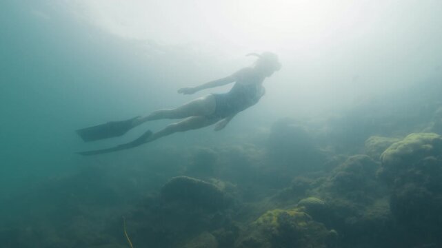 Young slim woman swims underwater, freediving and snorkeling in the sea near the coral reef near the island of Ilha Grande in Brazil