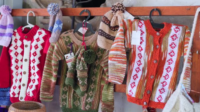 Hand knitted sweaters and winter hats with colorful geometric patterns displayed for sale at artisan market in Tapalpa Pueblo M&aacute;gico, Jalisco, Mexico. Close up shot.