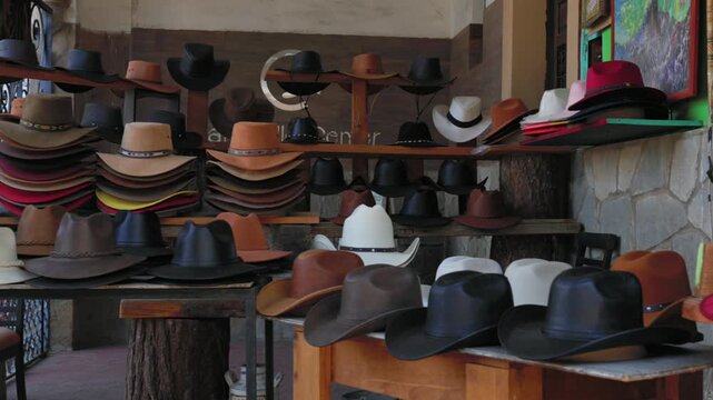 Traditional Mexican cowboy hats displayed at local shop in Tapalpa Pueblo M&aacute;gico, featuring colorful wide brim styles and regional fashion, Jalisco, Mexico. Pan right shot.
