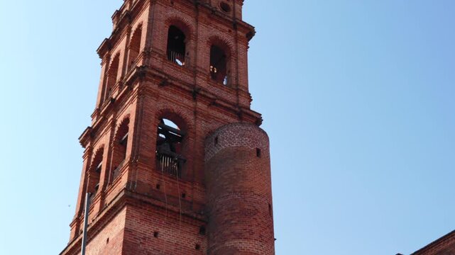 Nuestra Se&ntilde;ora de Guadalupe Church bell tower in Tapalpa Pueblo M&aacute;gico showcasing red brick architecture against clear blue sky, Jalisco, Mexico. Tilt up shot.