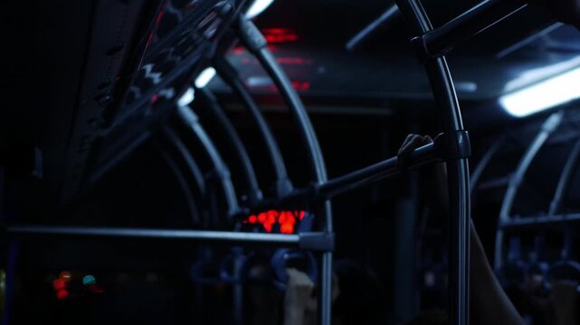 Crowded public bus interior with hanging handles and night city lights