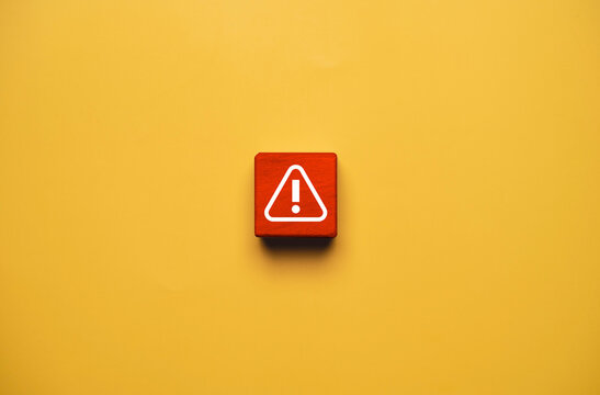 Warning and risk alert concept with red wooden block and exclamation symbol on yellow background representing danger caution, safety, problem detection, error and urgent attention.