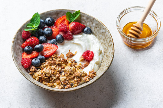 Granola bowl with greek yogurt, berries and honey for healthy breakfast.