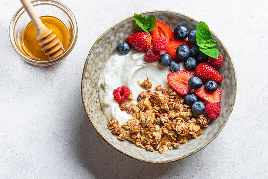 Granola bowl with greek yogurt, berries and honey for healthy breakfast.