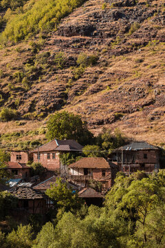 Traditional old houses made of mud, earth, and wood under a steep rocky hill in Topli Do village, showcasing authentic vernacular architecture at Stara Planina in Serbia 13.08.2026