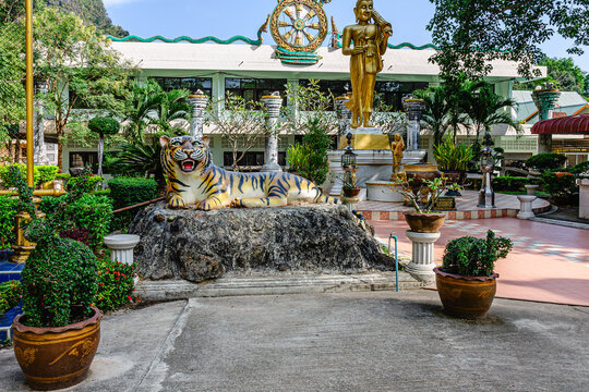 Colorful tiger statue resting by religious garden in southern Thailand near temple