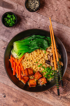 Noodles ramen miso soup served with tofu, bok choy, carrots, and mushrooms.