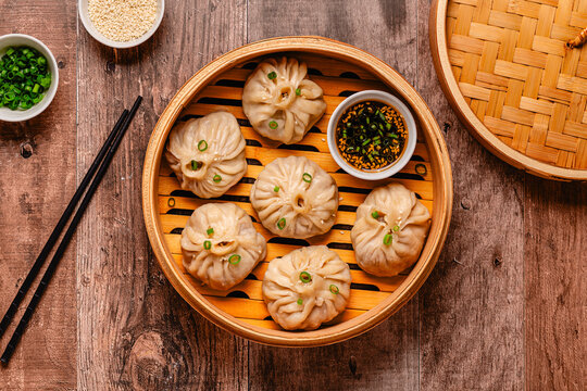 Steam basket with dumplings served with dipping sauce on a wooden table