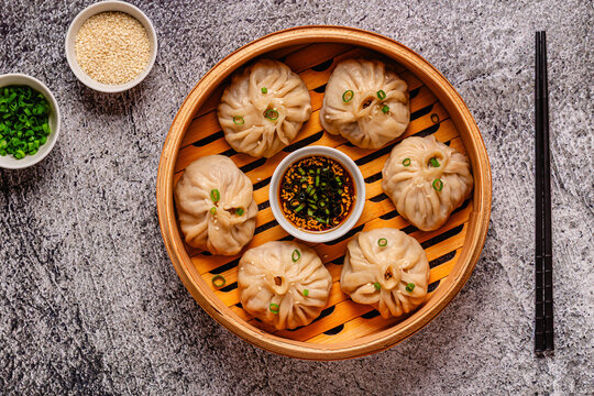 Steamed dumplings served in a bamboo basket with dipping sauce