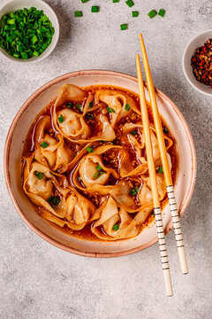 Wontons are placed in a bowl with spicy sauce.