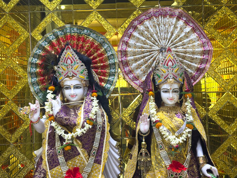Gilded altar with three ornate statues of Hindu deities adorned with garlands and umbrellas.