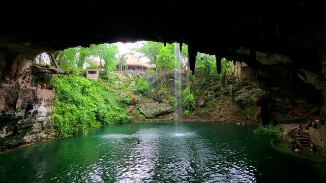 Stunning view of Ik Kil cenote with cascading waterfall and lush vegetation in Yucatan Mexico.