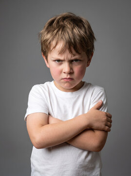  a 6-year-old Caucasian boy showing strong frustration, eyebrows lowered, lips pressed together and arms crossed firmly, children's behavior and emotional development concept