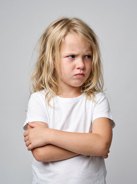  a 6-year-old Caucasian girl with an irritated and stubborn expression, arms folded across her chest, looking sideways with raised eyebrows,  children's behavior and emotional development concept