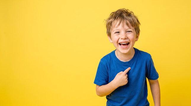 Happy boy smiling and pointing at himself against a bright yellow background